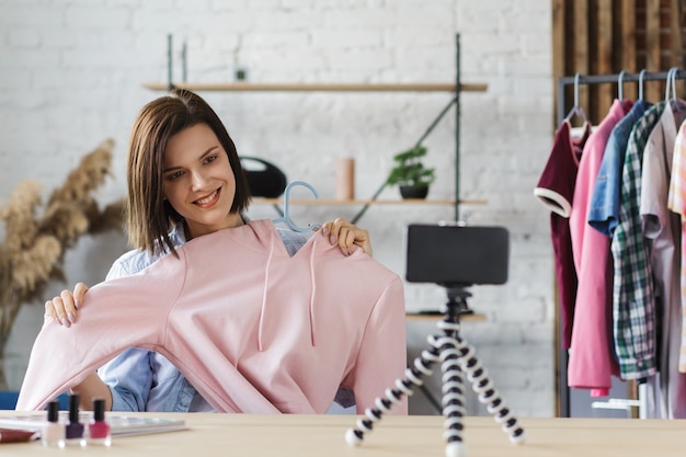 Jonge mooie vrouw blogger kleren tonen op camera