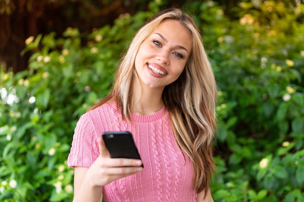 Jonge mooie vrouw buitenshuis met behulp van mobiele telefoon