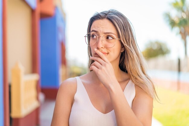 Jonge mooie vrouw buitenshuis met een bril en twijfels