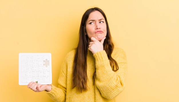 Jonge mooie vrouw denkt twijfelachtig en verward puzzelconcept te voelen