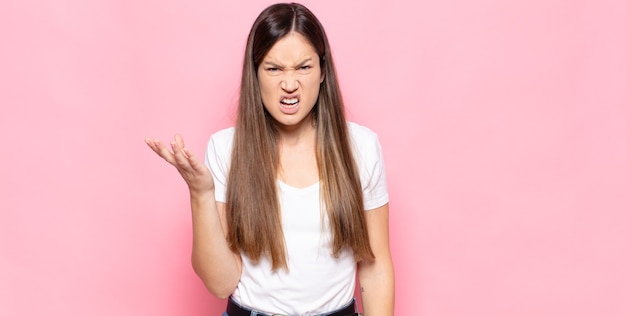 Jonge mooie vrouw die boos, geïrriteerd en gefrustreerd schreeuwt wtf