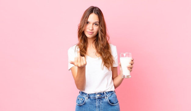 Jonge mooie vrouw die boos, opstandig en agressief voelt en een glas melk vasthoudt