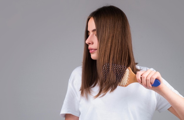 Jonge mooie vrouw die bruin haar kamt Haarverzorging Mooie brunette vrouw die haar borstelt met een haarborsel die gezond haar met een kam borstelt