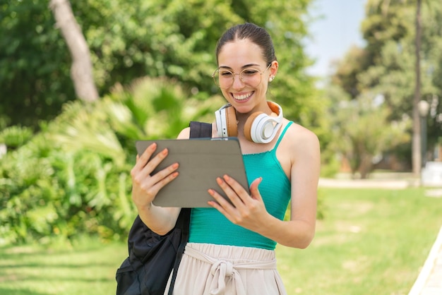 Jonge mooie vrouw die buitenshuis een tablet vasthoudt