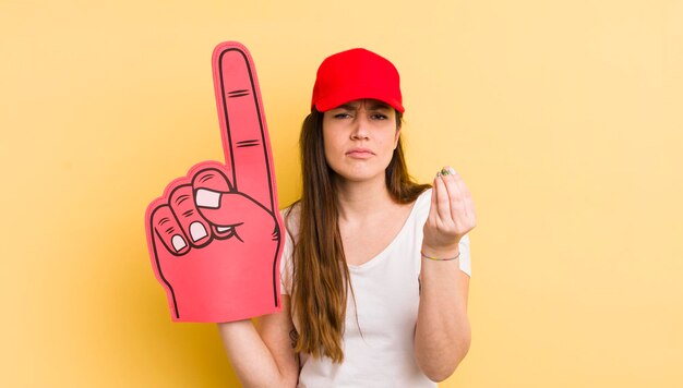 Foto jonge mooie vrouw die capice of geldgebaar maakt en je vertelt om het nummer één handconcept te betalen