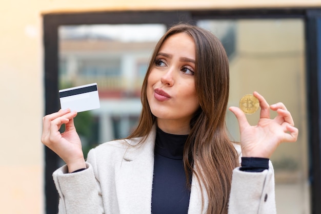 Jonge mooie vrouw die een Bitcoin in openlucht houdt