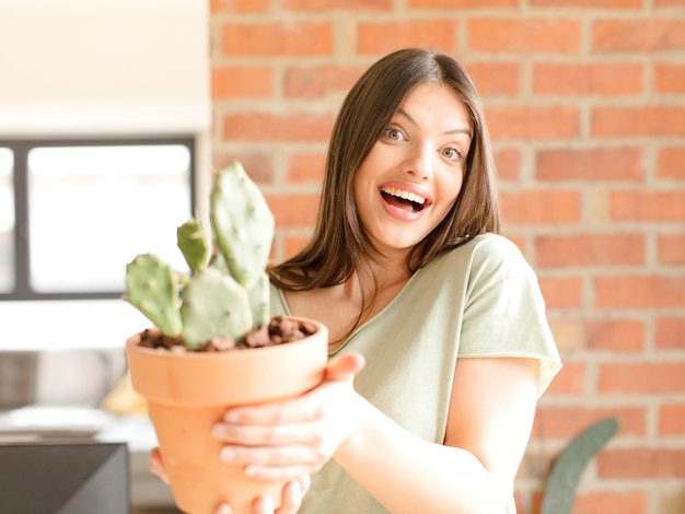 Jonge mooie vrouw die een cactus thuis houdt