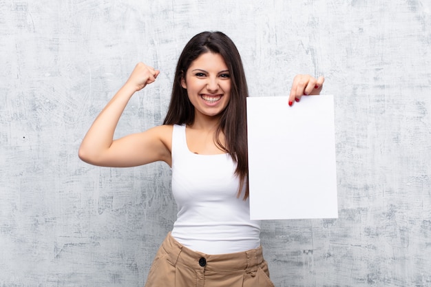 Jonge mooie vrouw die een document blad houdt tegen de muur van het grungecement