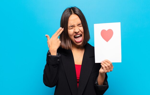 Jonge mooie vrouw die een hartkaart houdt