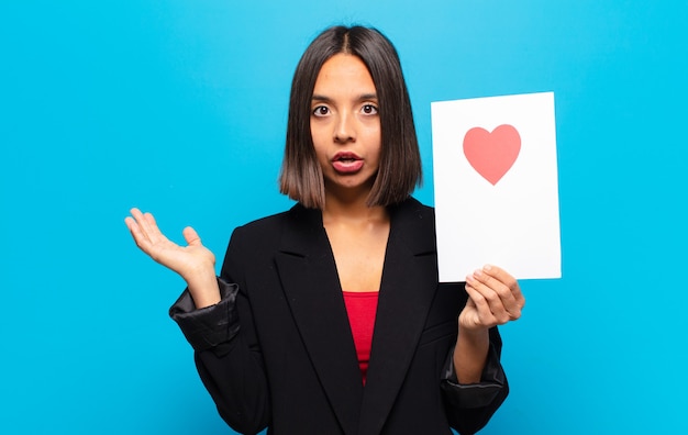 Jonge mooie vrouw die een hartkaart houdt