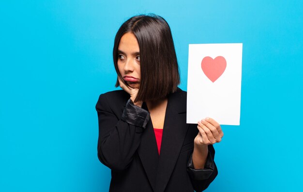 Jonge mooie vrouw die een hartkaart houdt