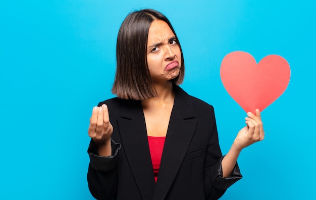 Jonge mooie vrouw die een hartkaart houdt