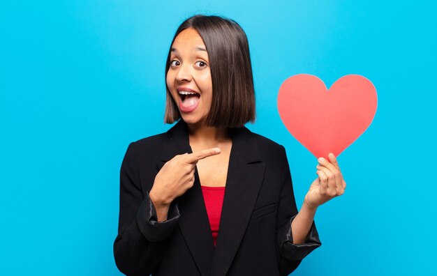 Jonge mooie vrouw die een hartkaart houdt