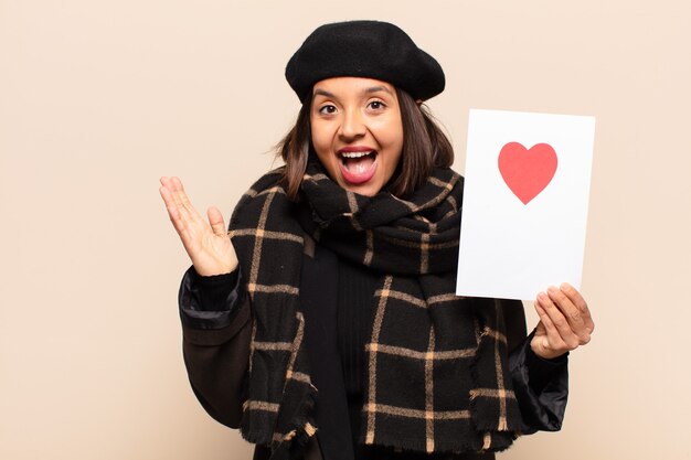 Jonge mooie vrouw die een hartkaart houdt