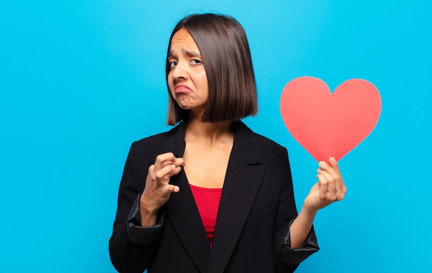 Jonge mooie vrouw die een hartkaart houdt