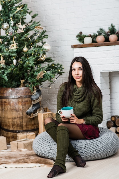 Jonge mooie vrouw die een kop met een hete drank houdt