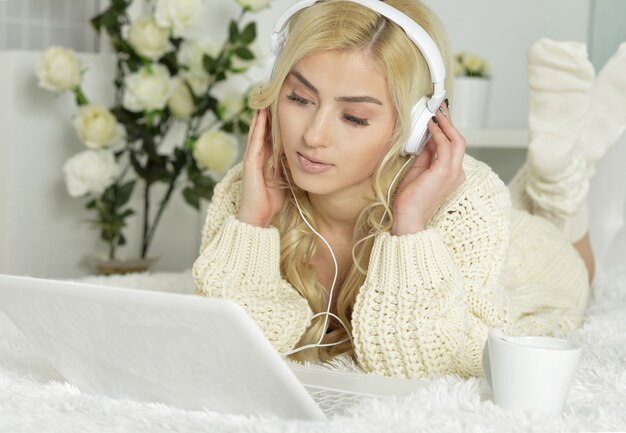 Jonge mooie vrouw die een laptopcomputer thuis met behulp van