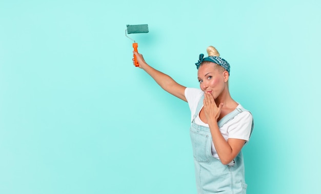 Jonge mooie vrouw die een muur schildert met een roller