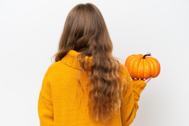 Jonge mooie vrouw die een pompoen houdt die op witte achtergrond in achterpositie wordt geïsoleerd