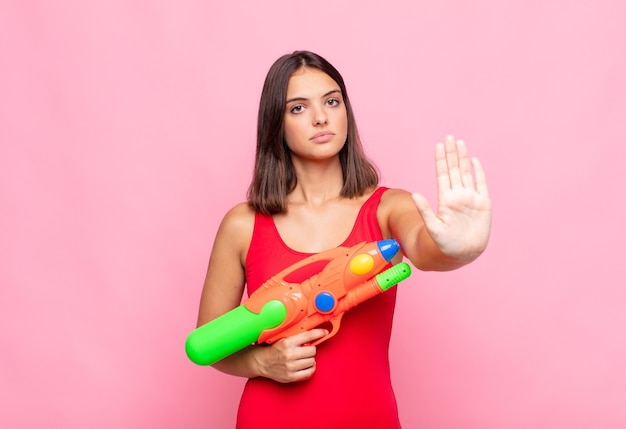 Jonge mooie vrouw die er serieus, streng, ontevreden en boos uitziet en een open palm laat zien die een stopgebaar maakt