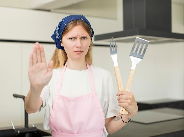 jonge mooie vrouw die er serieus uitziet en open handpalm laat zien die het concept van de thuischef-kok maakt