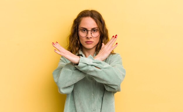 Jonge mooie vrouw die geïrriteerd en ziek van je houding kijkt en zegt dat er genoeg handen gekruist zijn om te zeggen dat je moet stoppen