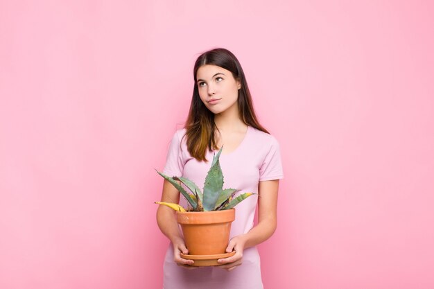 Jonge mooie vrouw die gelukkig glimlacht en dagdroomt of twijfelt, kijkend aan de kant met een installatie