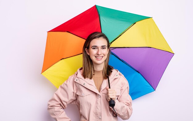 Jonge mooie vrouw die gelukkig lacht met een hand op de heup en zelfverzekerd. paraplu concept