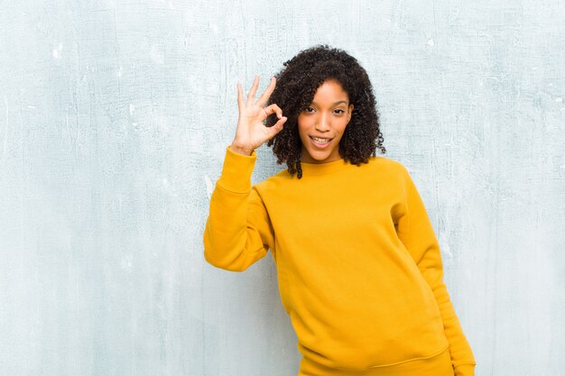 Jonge mooie vrouw die gelukkig, ontspannen en tevreden voelt, goedkeuring toont met ok gebaar, glimlachend