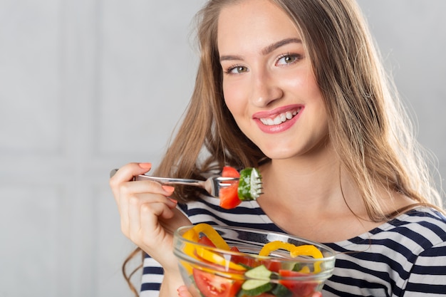 Jonge mooie vrouw die gezond voedsel eet - salade