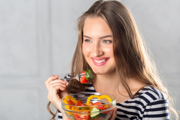 Jonge mooie vrouw die gezond voedsel eet - salade