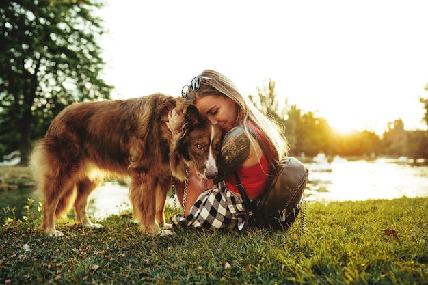 Jonge mooie vrouw die haar schattige hond aait in het park