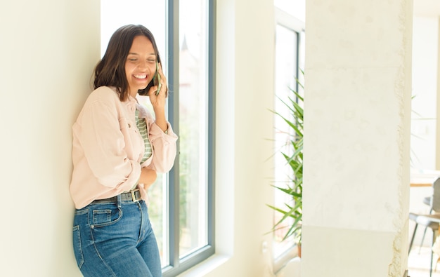 Jonge mooie vrouw die haar telefoon thuis gebruikt