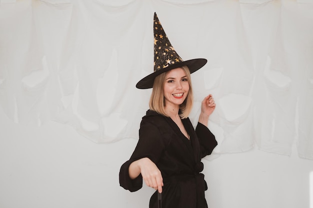 Jonge mooie vrouw die het kostuum van heksenhoed halloween op witte achtergrond draagt