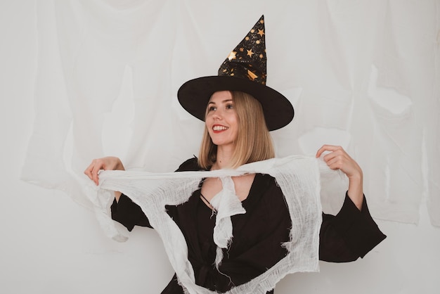 Jonge mooie vrouw die het kostuum van heksenhoed halloween op witte achtergrond draagt