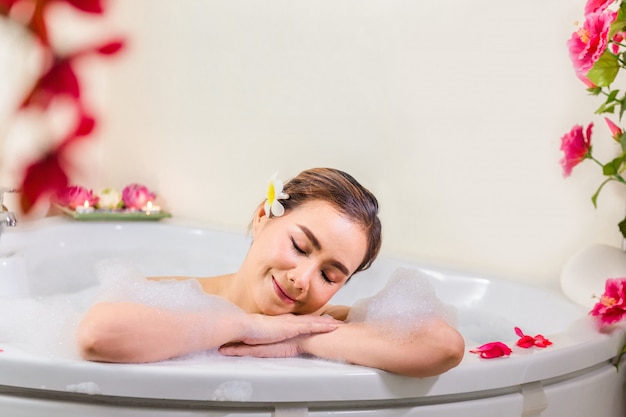 Foto jonge mooie vrouw die in badkuip bij kuuroordsalon genieten van