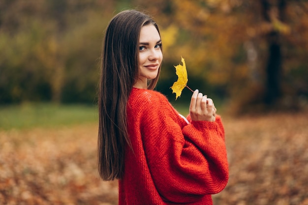 Jonge, mooie vrouw die in het herfstpark loopt en bladeren vasthoudt