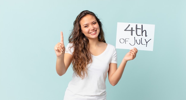 Jonge mooie vrouw die lacht en er vriendelijk uitziet, met het nummer één concept van de onafhankelijkheidsdag