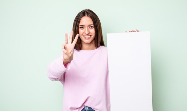 Jonge mooie vrouw die lacht en er vriendelijk uitziet met nummer drie leeg canvasconcept