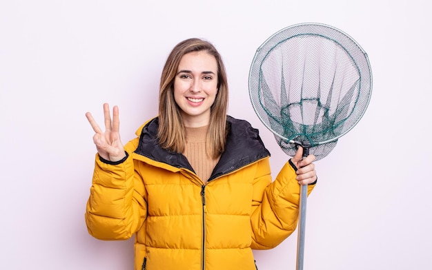 Jonge mooie vrouw die lacht en er vriendelijk uitziet met nummer drie vissersconcept