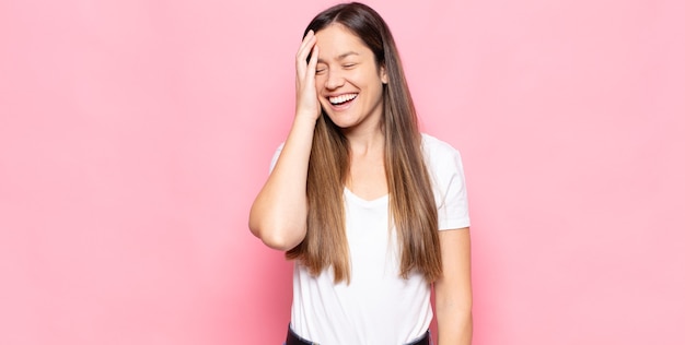 Jonge mooie vrouw die lacht en op haar voorhoofd slaat alsof ze dâ € ™ oh! ik was het vergeten of dat was een domme fout