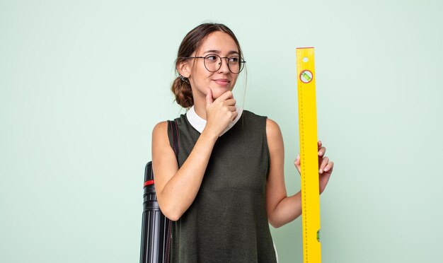 Jonge mooie vrouw die lacht met een gelukkige, zelfverzekerde uitdrukking met de hand op de kin. architectuur concept