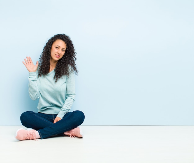 Jonge mooie vrouw die lacht vrolijk en vrolijk, zwaaiende hand