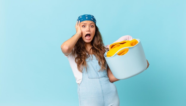 Jonge mooie vrouw die met de handen in de lucht schreeuwt en een wasmand vasthoudt