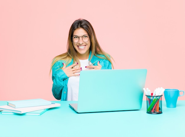 Jonge mooie vrouw die met laptop werkt die gelukkig, verrast, trots en opgewekt kijkt, die aan zelf richt