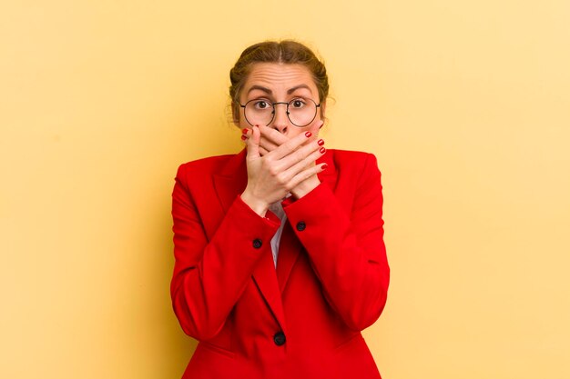 Jonge mooie vrouw die mond bedekt met handen met een geschokt bedrijfsconcept