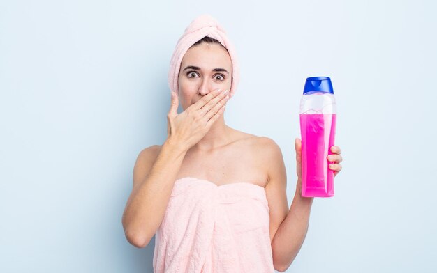 Jonge mooie vrouw die mond bedekt met handen met een geschokt. douche en shapoo concept