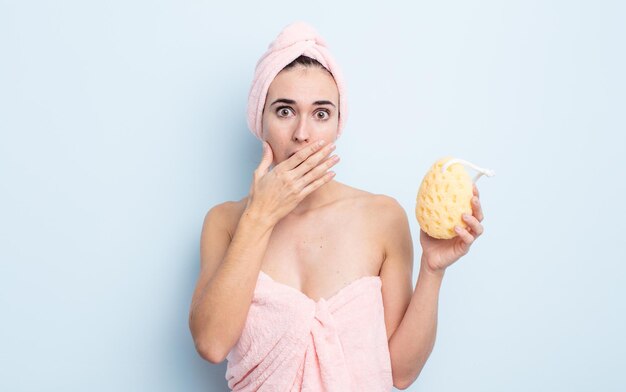 Jonge mooie vrouw die mond bedekt met handen met een geschokt. douche en spons concept