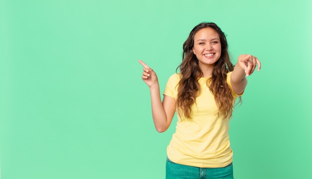 Jonge mooie vrouw die naar de camera wijst die jou kiest en naar de kopieerruimte wijst