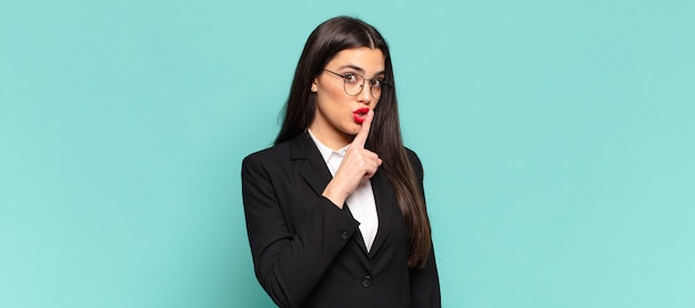 Jonge mooie vrouw die om stilte en stilte vraagt, met de vinger voor de mond gebarend, shh zegt of een geheim houdt